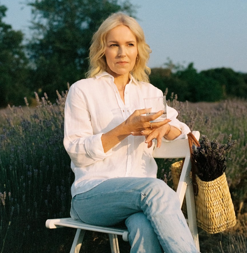 Berit Nordstrand sitting in a lavender field holding a glass of water